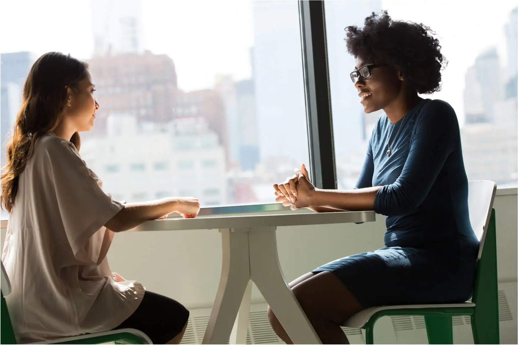 two women sitting across a table discussing something